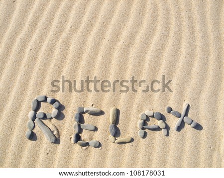 Word relax written in sand on a sunny day