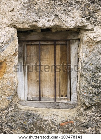 Old window closed with a draw and some bars. Rolling Window is a stone house