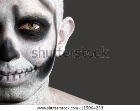 face painted with a skull. The photo shows a young man with painted face face painted with a skull. Halloween makeup.