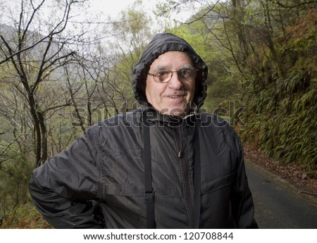 Mature man with a raincoat and glasses in nature