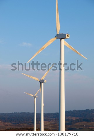 Three wind turbines in a landscape, vertical composition.