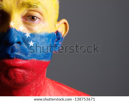Man face painted with venezuelan flag. The man is sad and photographic composition leaves only half of the face.
