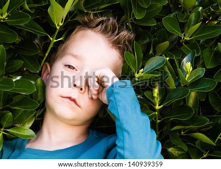 Blond boy rubbing his eyes. The child is sleepy and tired.