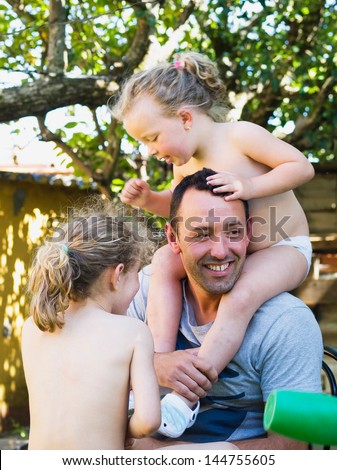 Father playing with his two daughters outdoors in a sunny day