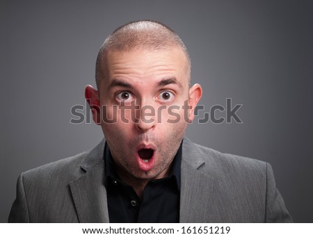 Businessman with surprised expression and isolated on dark background