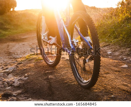 Low Angle View Of Cyclist Riding Mountain Bike On Rocky Trail At Sunrise