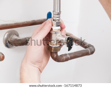 Man repairing a safety valve of an electric boiler inside home