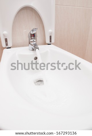 Chrome mixer tap with water in a bathroom.