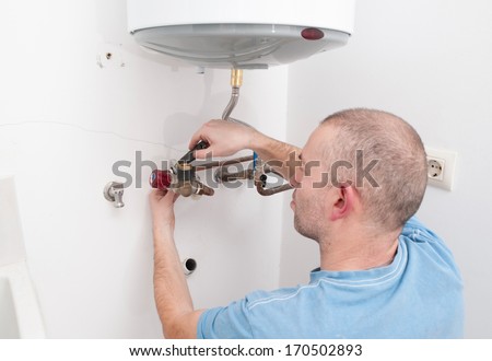 Plumber repairing an electric boiler inside home