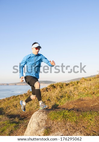 Man practicing trail running with a coastal landscape in the background