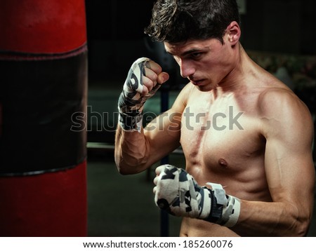 Young caucasian Boxer training with a punching bag in his home gym