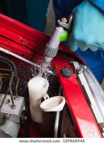 Man filling the water tank of the car in a garage