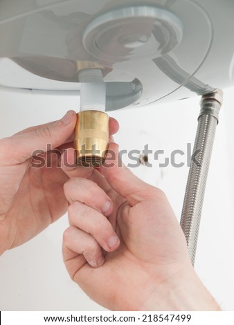 Hands repairing the plumbing pipes of an electric boiler at home