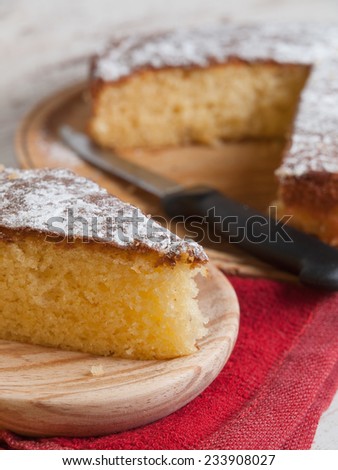 Portion of a sponge cake on a wooden plate in a studio shot.
