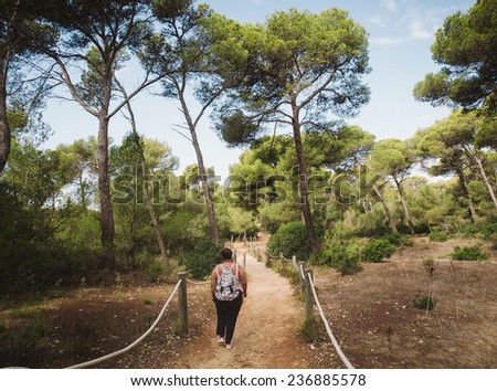 Woman walking in a path in a mediterranean forest in Menorca, Spain.
