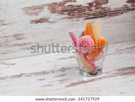 jelly beans in a glass cup with copy space on wooden background