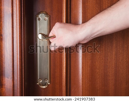 Hand gripping the handle of a door inside home