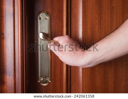 Hand gripping the handle of a door inside home