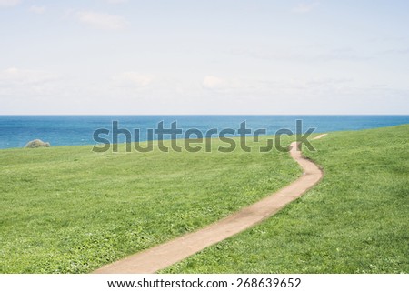 Field, path, sea and sky in horizontal composition.