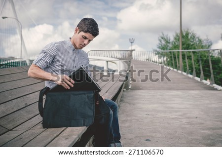 Young man taking his laptop on a black bag outdoors