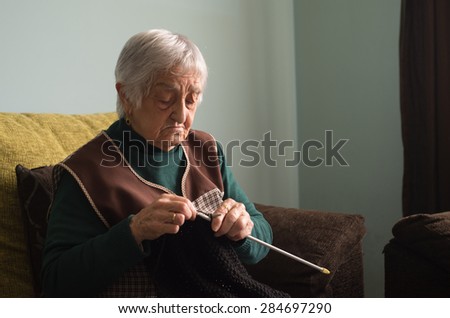 Elderly woman knitting at home. Woman is focus in her activity.