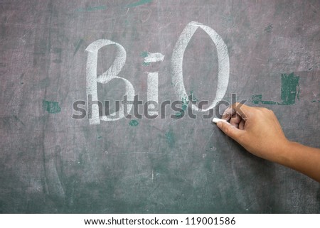 hand with chalk writing \'Bio\' in the blackboard