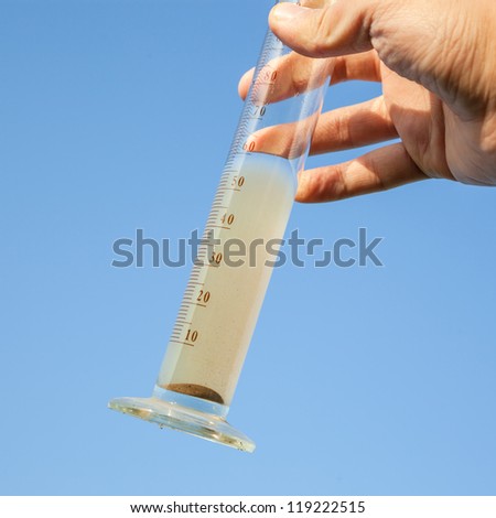 hand hold graduation cylinder with soil solution in it in the sky