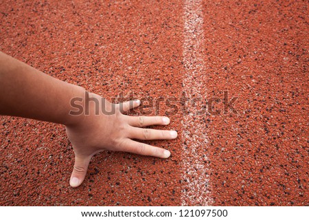 red running track field with white lines,a man\'s hand on ground ,start to run
