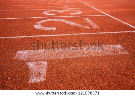 red running track field with white lines and numbers