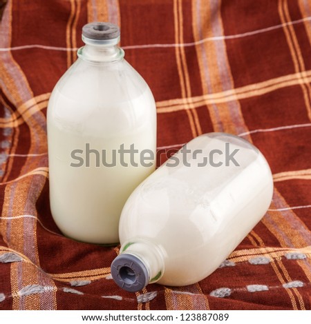 milk in glass bottle with brown cloth as background