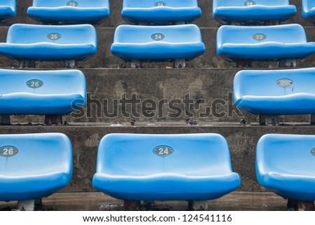 blue rubber seats in a sport stadium in the out door under rain, with a missing seat
