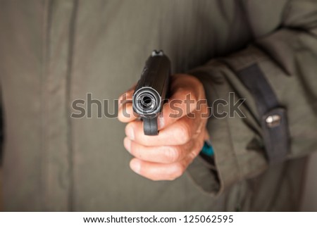 old man hold a pistol pointing to the camera