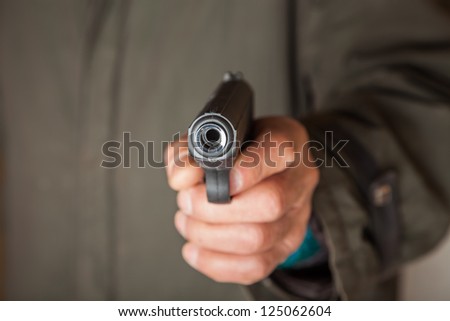 old man hold a pistol pointing to the camera