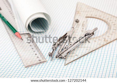 drawing compass and ruler on table with grid sheet
