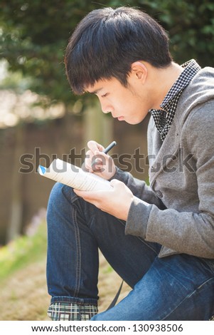asian male studying in the park