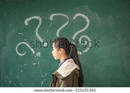 asian female student with lots of question marks in front of blackboard