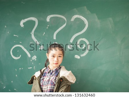 asian female student with lots of question marks in front of blackboard