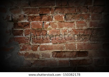 Texture of the old red brick wall with concrete interbrick seams highlighted by dim light lamp