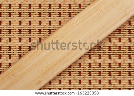 Asian natural ecological material concept. Diagonal wood table plank over flax thread wired bamboo mat background in shades of beige