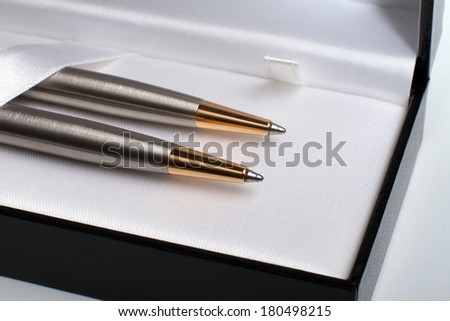Close up of gift pack of ballpoint pen set made from brushed silver steel with gold in black opened box on white background