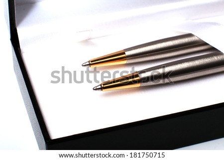 Close up of gift pack of ballpoint pen set made from brushed silver steel with gold in black opened box on white background