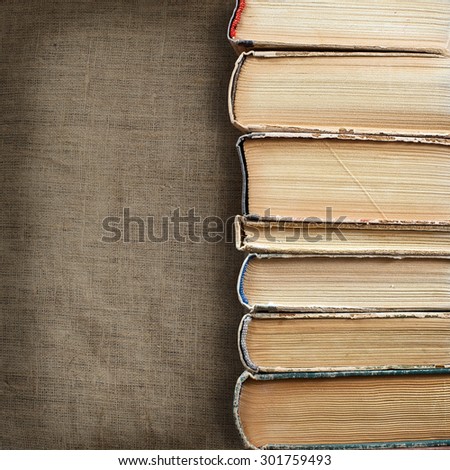 Design concept of wisdom and knowledge power - close up view on stacked old books placed on dimmed fabric canvas natural linen texture background. Clipping path included