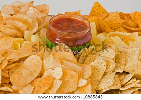 Pile of assorted potato chips with a bottle of tasty salsa dip