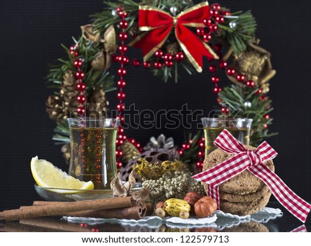 Hot tea with lemon and biscuits in front of a Christmas wreath isolated on black