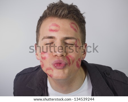 Funny portrait of young man covered with lipstick kisses