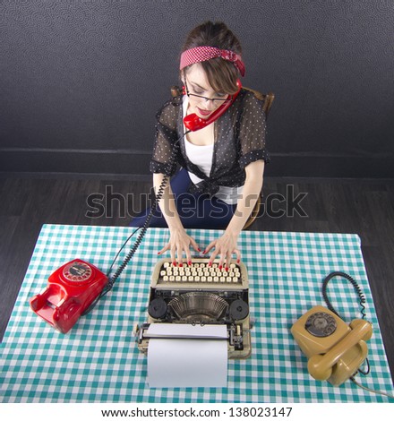 Sexy pin up secretary sitting at a desk talking on phone and typing on typewriter