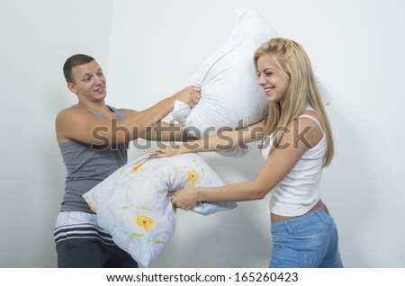 Couple fighting together with pillows in bed