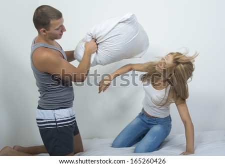 Couple fighting together with pillows in bed