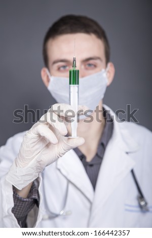 Doctor with a green liquid in the syringe. Focus on syringe