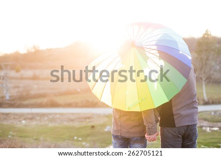 Happy same sex couple under rainbow umbrella